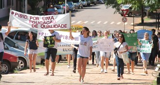 A foto é de uma manifestação do PIBID em 2016, na praça central de Cerro Largo. Os pibidianos carregam cartazes com dizeres como "Pibid, por uma educação de qualidade".