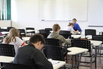 Foto de adolescentes em sala de aula, resolvendo a prova
