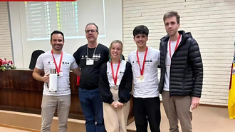 Imagem dos três estudantes - dois homens e uma mulher -, além do professor, com medalhas no peito, e um homem com um crachá