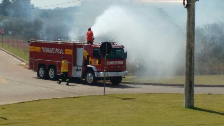 Bombeiro em cima de caminhão combate as chamas na mata com água