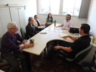 Foto com seis pessoas em volta de uma mesa durante reunião