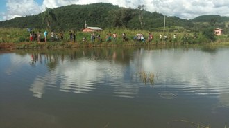 Grupo de pessoas pescando em frente ao tanque de cultivo de peixes