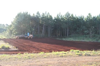 Na imagem a máquina está fazendo a terraplanagem no terreno destinado ao campo de futebol.