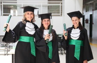 Na foto três formandas seguram o canudo recebido durante a colação de grau.