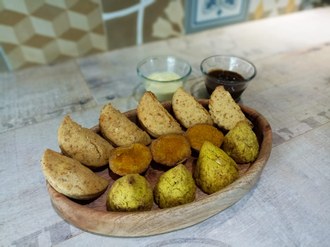 Fotografia mostra os salgados em uma bandeja sobre uma mesa.