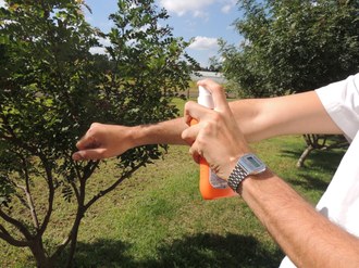 Foto mostra uma pessoa aplicando repelente nos braços.