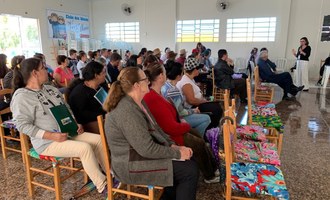 Na imagem várias pessoas estão sentadas assistindo palestra que ocorro em auditório.