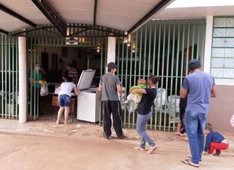 Na imagem algumas pessoas aguardam em fila para recebimento das cestas.