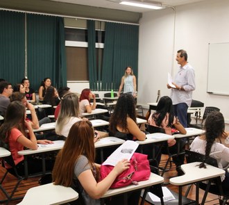 Estudantes sentados acompanham apresentação do professor em sala de aula.