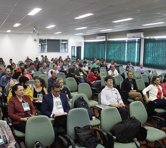 Várais pessoas sentadas numa sala assistindo a uma palestra